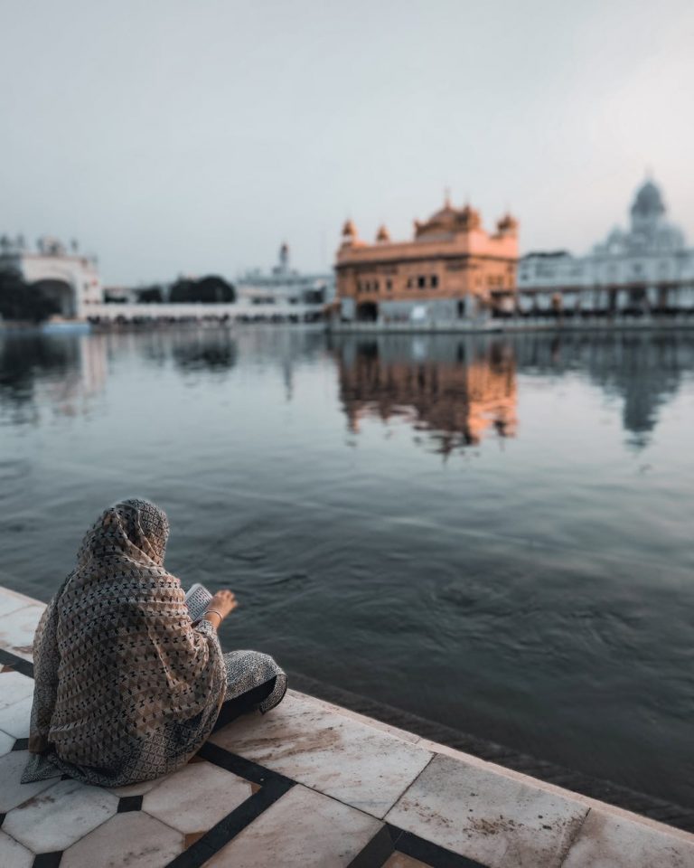 unrecognizable woman sitting near pond