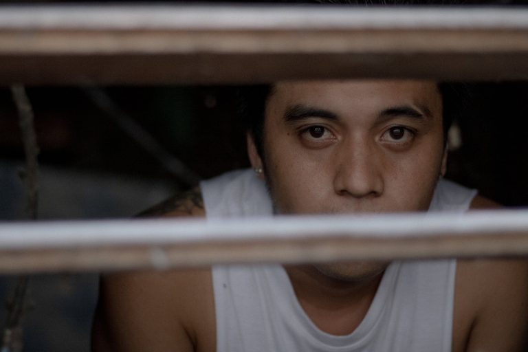 crop ethnic prisoner behind jail bars in daylight