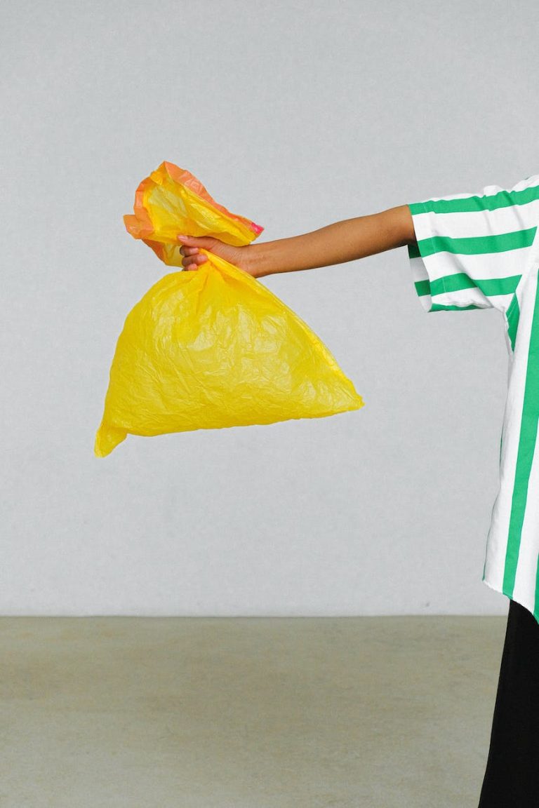 woman in white and green shirt holding yellow plastic bag