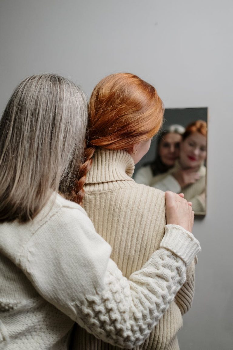 a mother and daughter looking at their reflection in the mirror