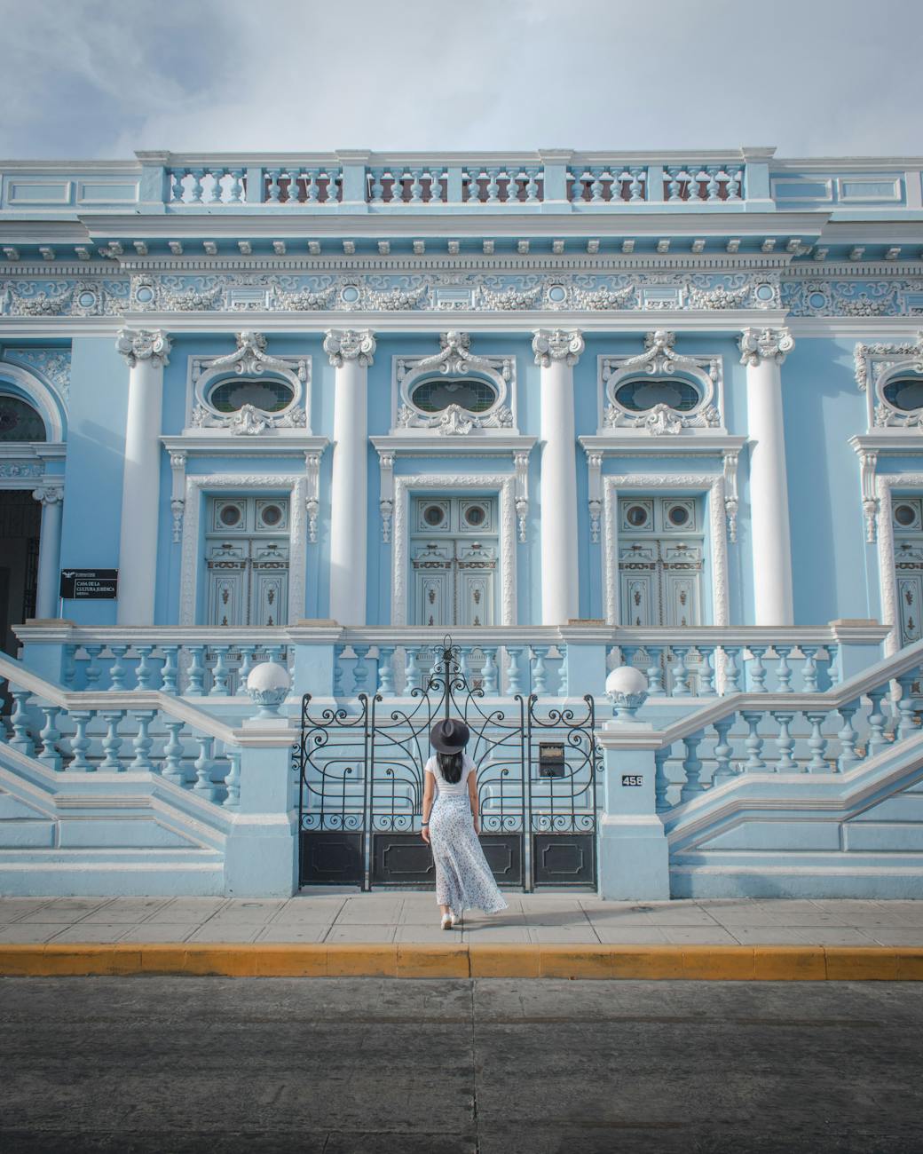 woman in white dress standing in front of culture centre in merida mexico