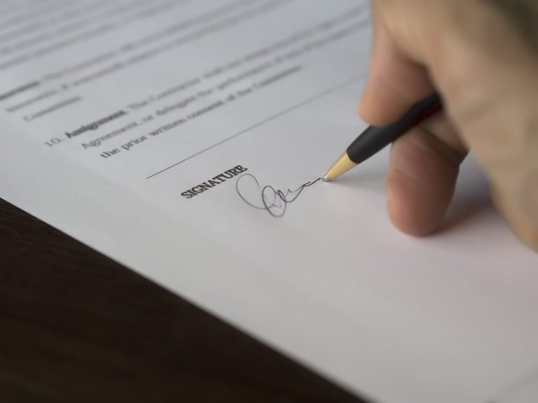 selective focus photography of person signing on paper